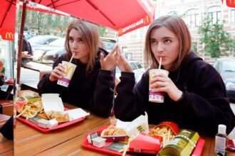 Joven disfruta comida en McDonald’s mientras participa en la promoción digital Monopoly desde la app oficial.
